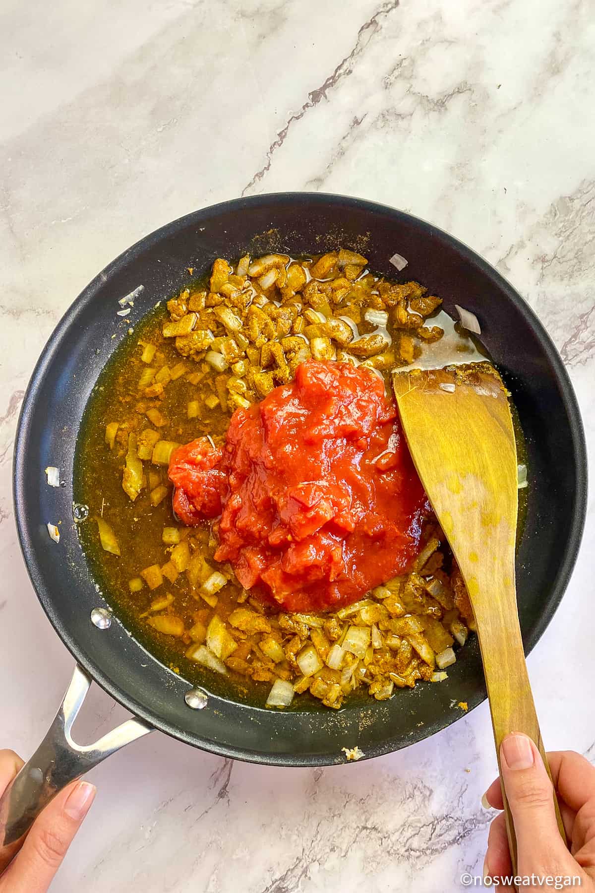 Tomatoes and broth added to onions in a skillet.