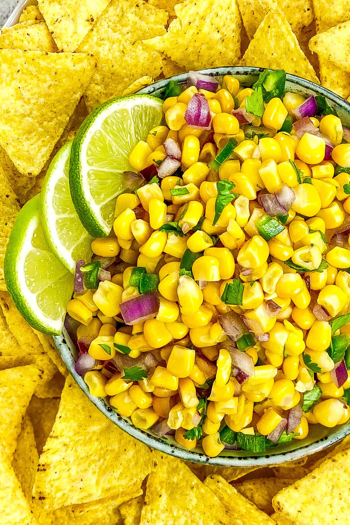 Corn salsa in a bowl with three limes.