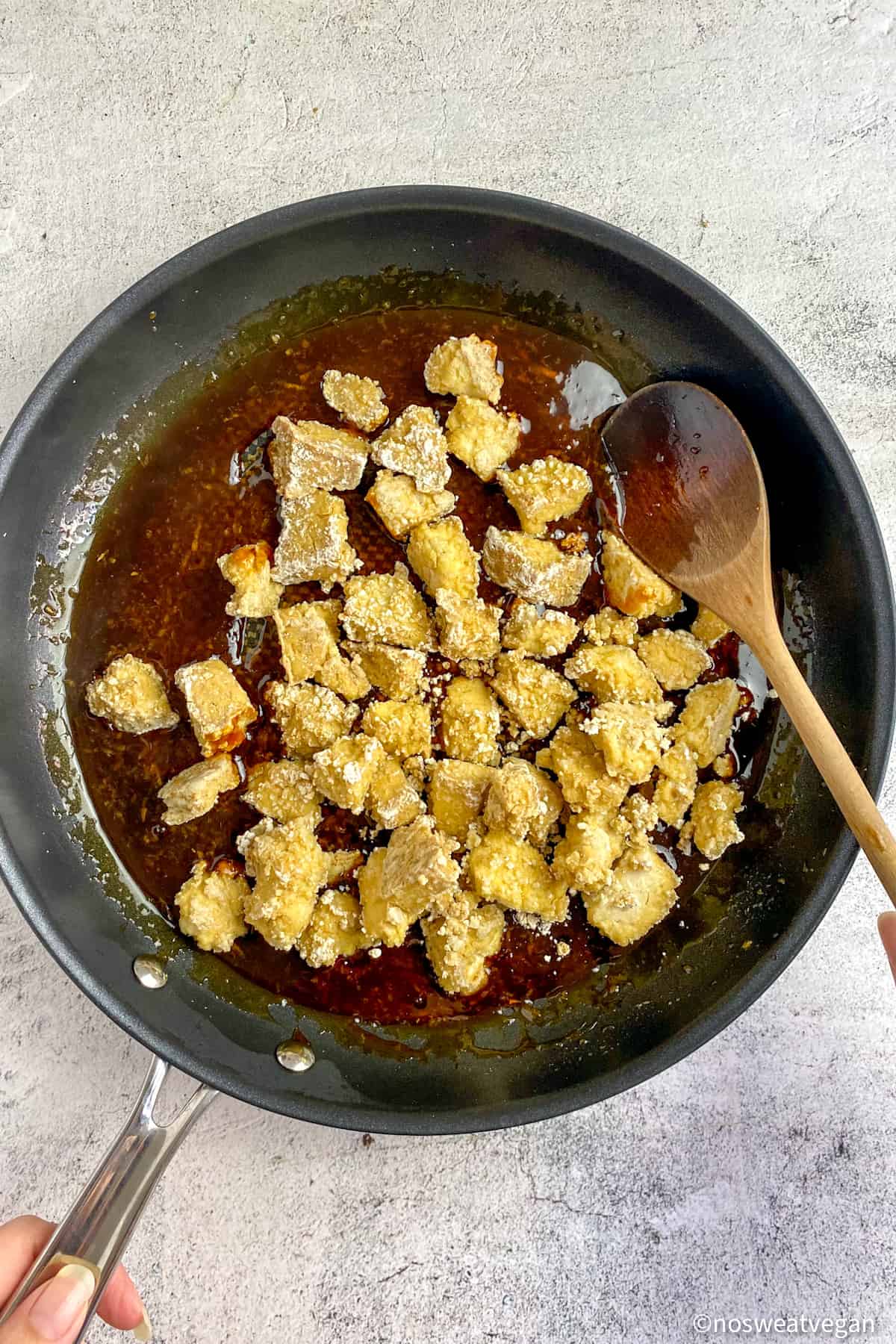 Crispy tofu in a skillet with teriyaki sauce, unmixed.