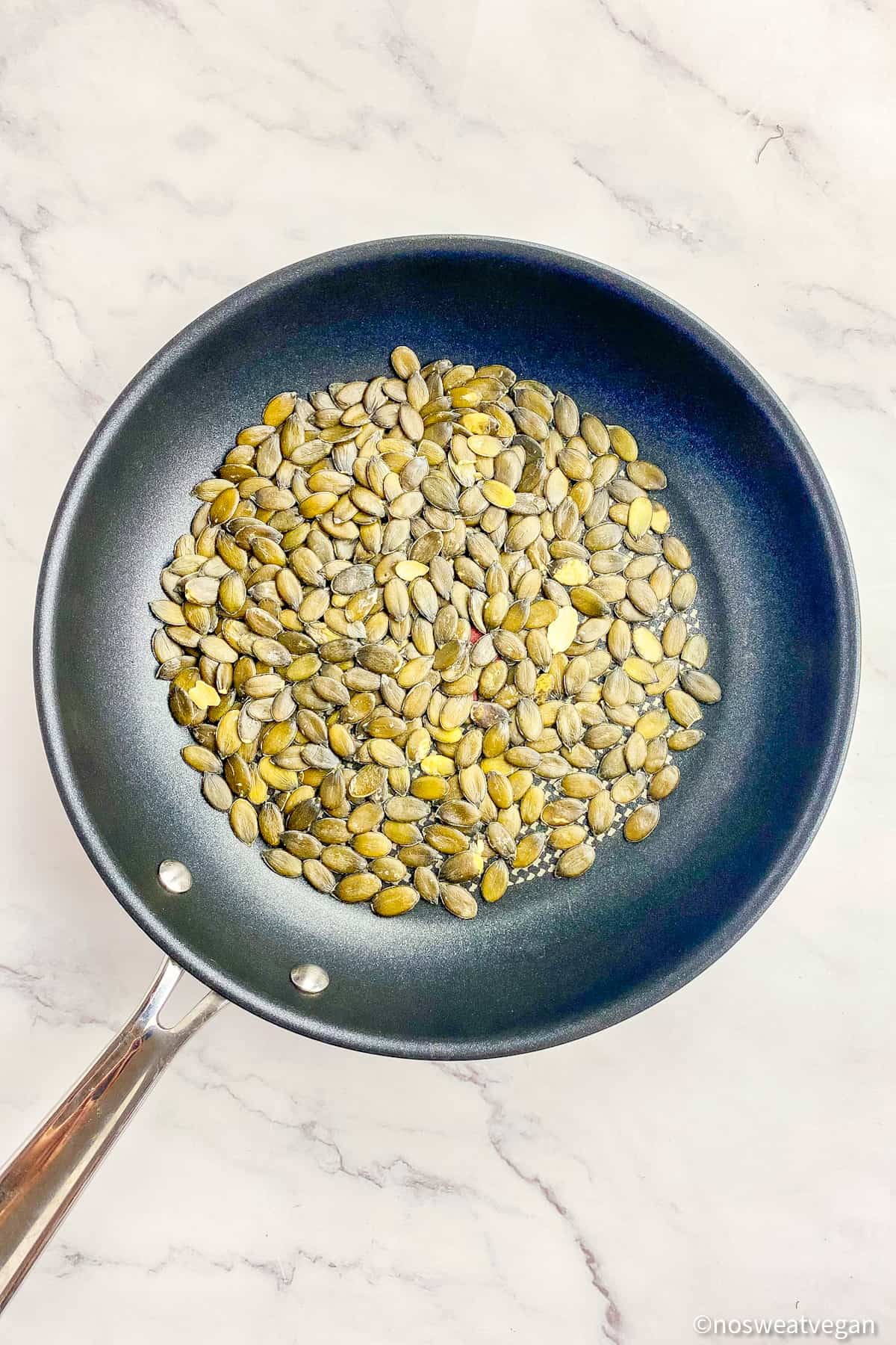 Toasted pumpkin seeds in a skillet.