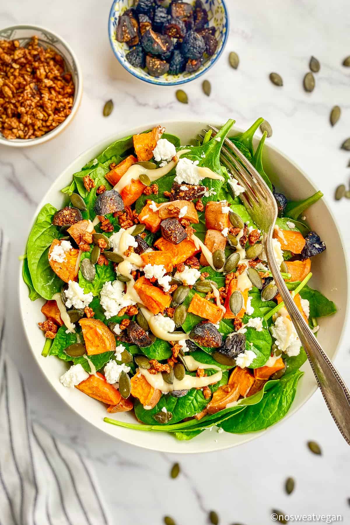 Spinach salad with sweet potatoes and apple cider dressing in a bowl with a fork.