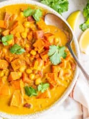 Sweet potato and chickpea curry in a bowl with a spoon.