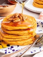 Vegan sweet potato pancakes on a plate with syrup pouring over.