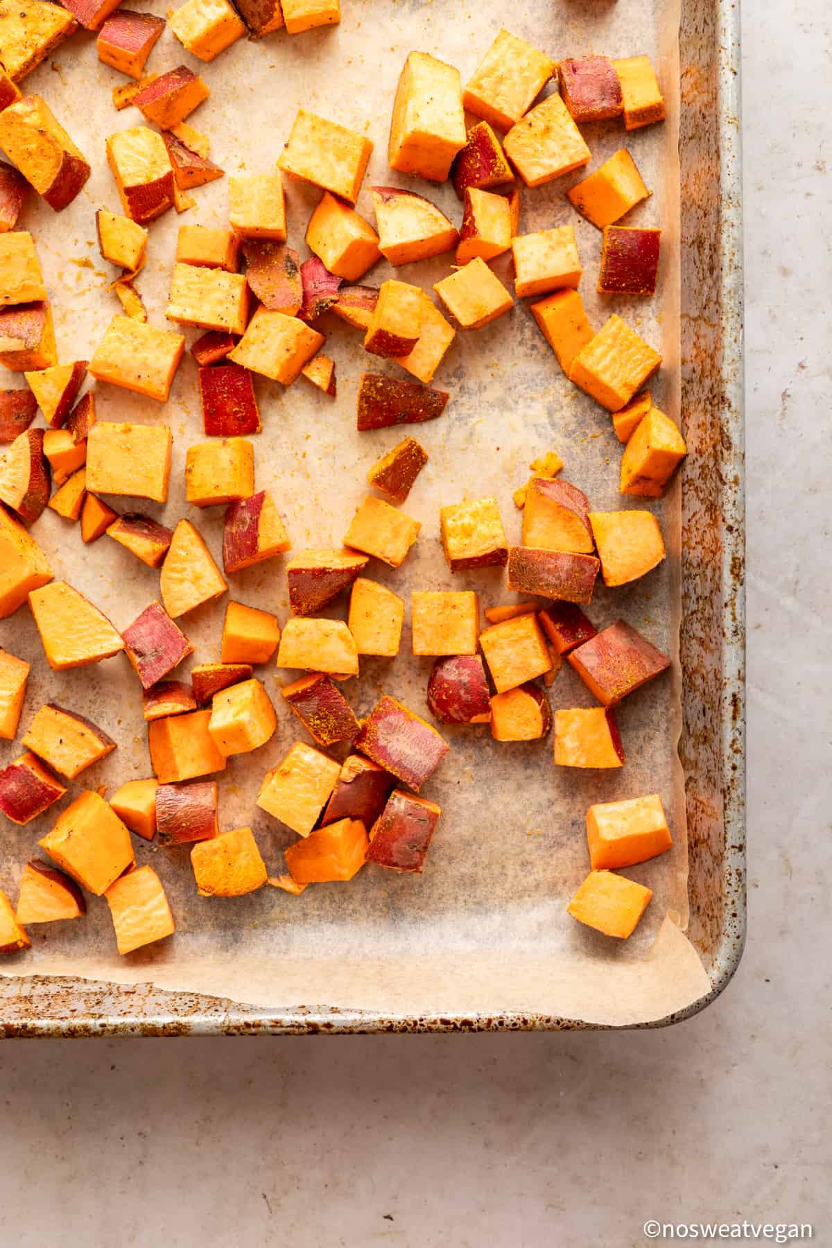 Roasted sweet potato cubes on a baking sheet.