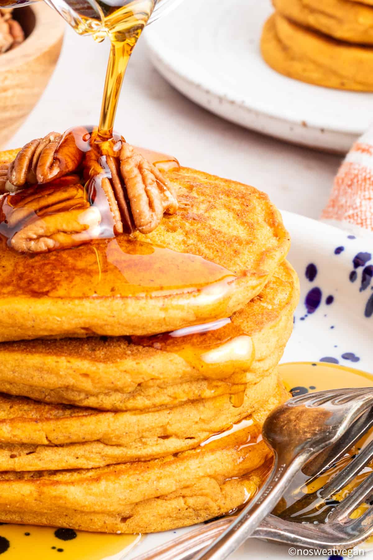 Vegan sweet potato pancakes on a plate with syrup pouring over.