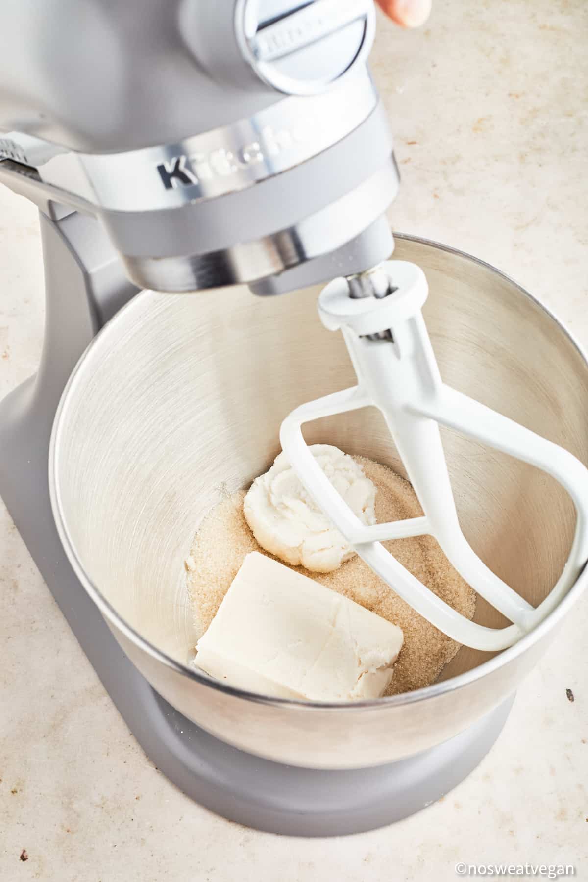 Creaming vegan butter, cream cheese, and sugar in a mixer.