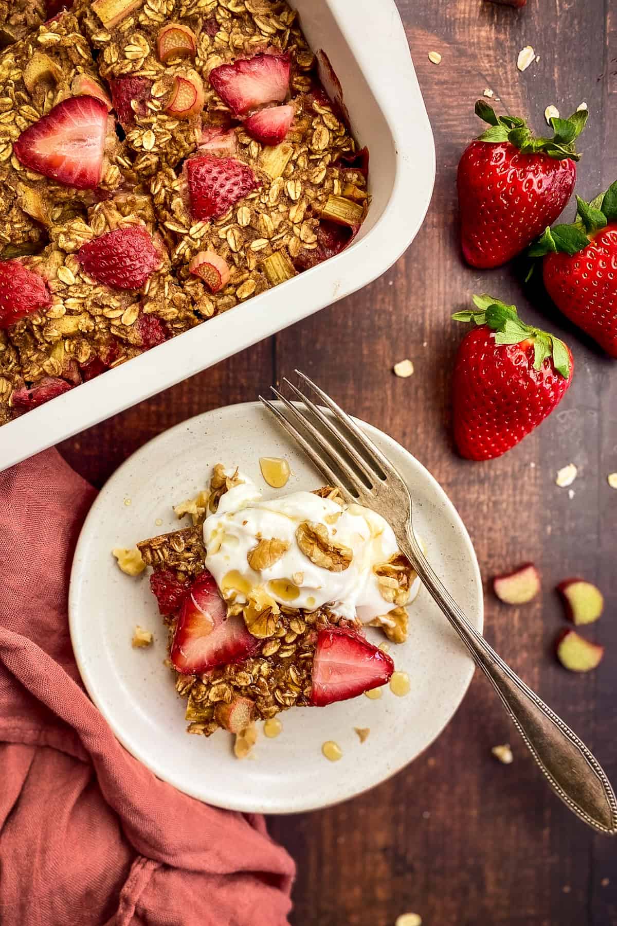 Rhubarb baked oatmeal on a plate next to a baking dish.