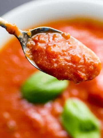 Spoon lifting up from a bowl of tomato soup.