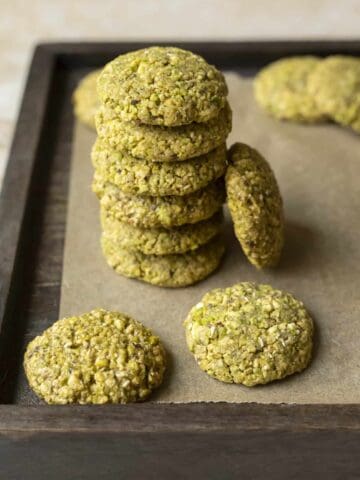 Vegan pistachio cookies stacked on a tray.
